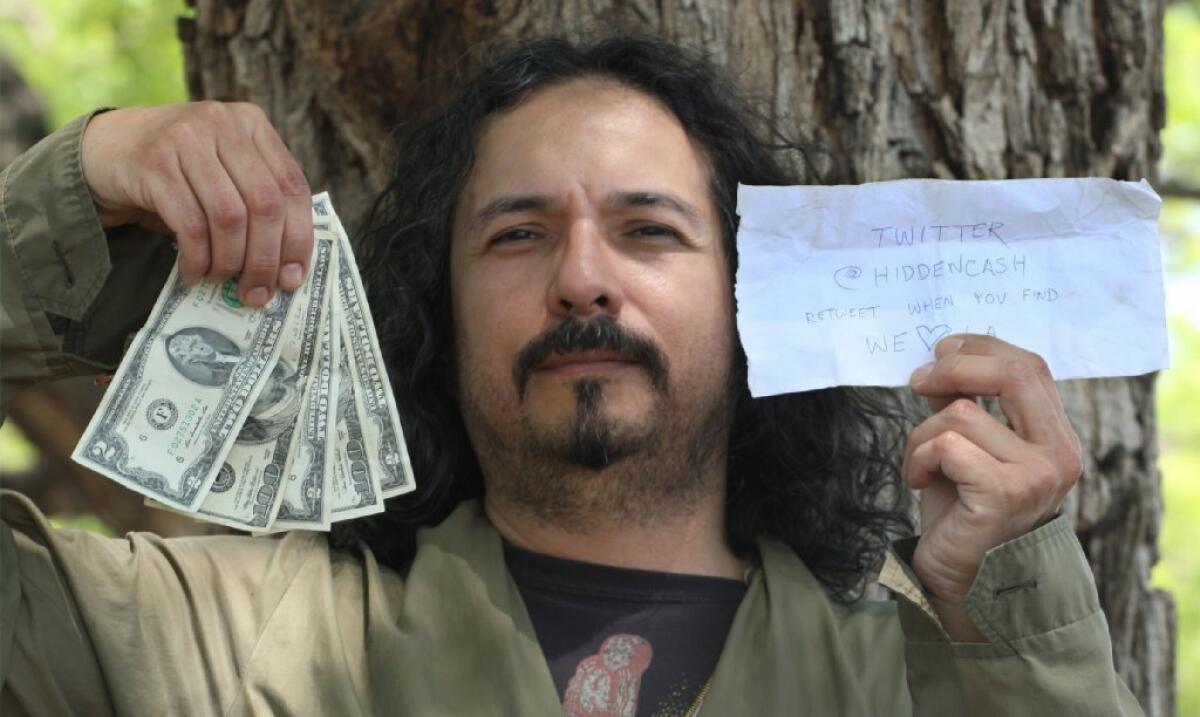 Robert Ramirez holds up $206 he found in an envelope in a tree in the parking lot of the Huntington Library in San Marino.