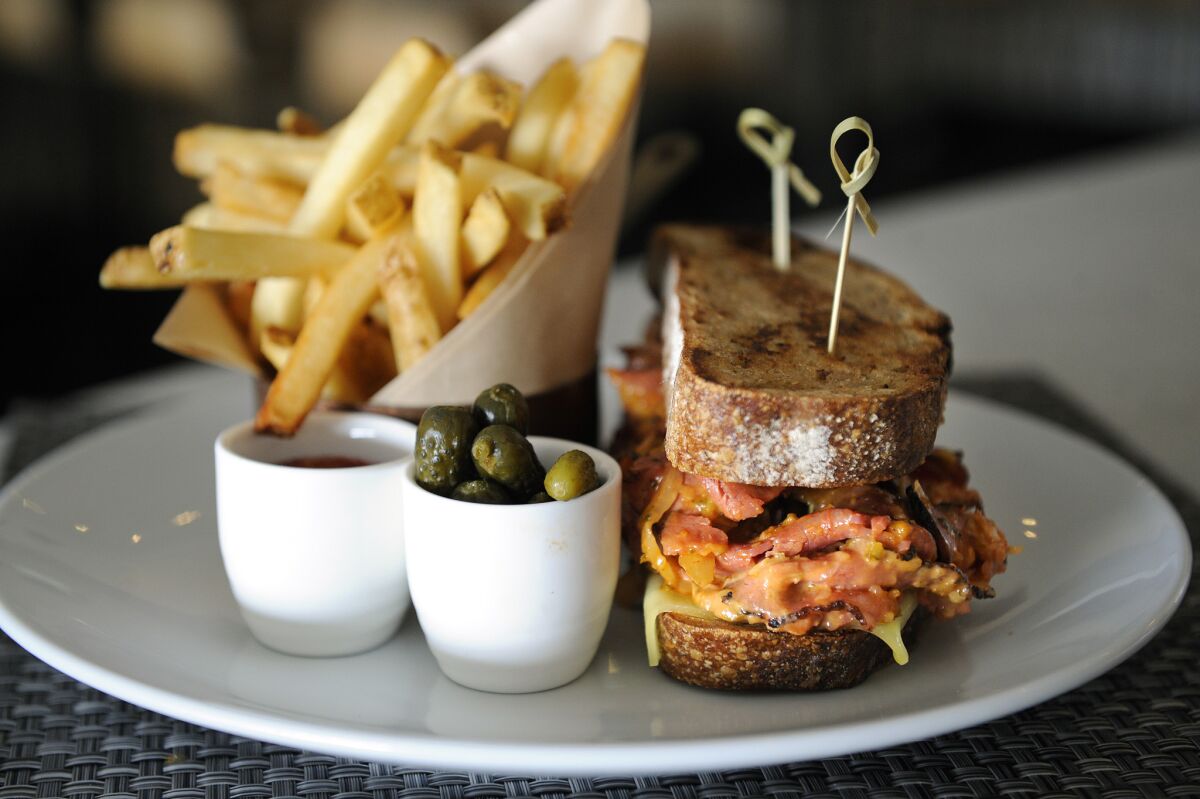 Birch's grilled cheese Reuben made with pastrami, bacon sauerkraut and Russian dressing is served with fries and pickles.