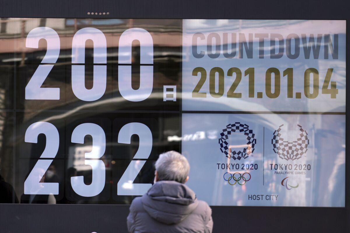 A man looks at a countdown calendar showing 200 day to start Tokyo 2020 Olympics Monday, Jan. 4, 2021, in Tokyo. The countdown clock for the postponed Tokyo Olympics hit 200 days to go on Monday. Also on Monday, Japanese Prime Minister Yoshihide Suga said he would consider calling a state of emergency as new coronavirus cases surge to record numbers in Tokyo and neighboring prefectures.(AP Photo/Eugene Hoshiko)