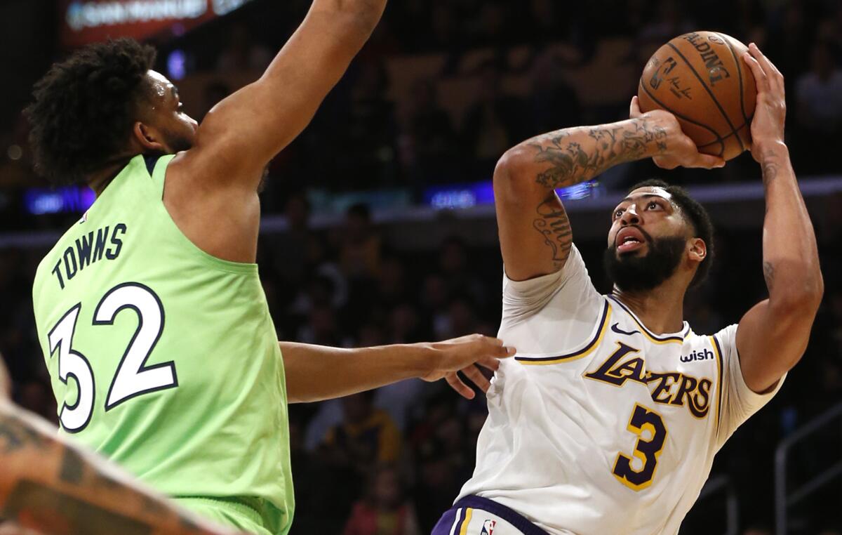 Anthony Davis takes a shot as Minnesota's Karl-Anthony Towns defends on Sunday at Staples Center.