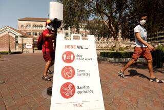 LOS ANGELES, CA - AUGUST 17, 2020 - - USC student Ashish Kulkarni, 24, takes a handful of antibacterial gel, as student Vijay Ugru, 25, looks over three steps to keep the coronavirus at bay on the first day of academic instruction for the Fall 2020 semester on the USC campus in Los Angeles on August 17, 2020. Students were taking online courses off campus due to the coronavirus pandemic and the university was nearly empty. (Genaro Molina / Los Angeles Times)