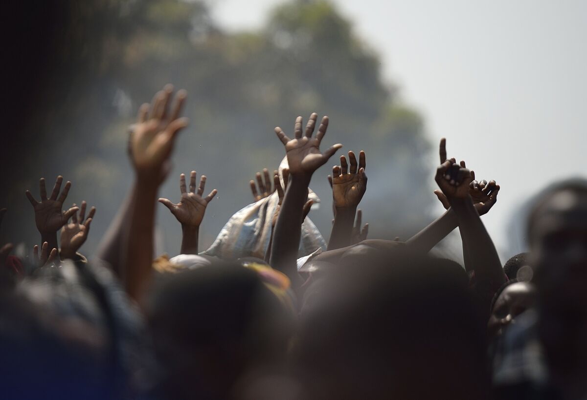 Displaced people raise their hands as they wait for food distribution in central Africa.