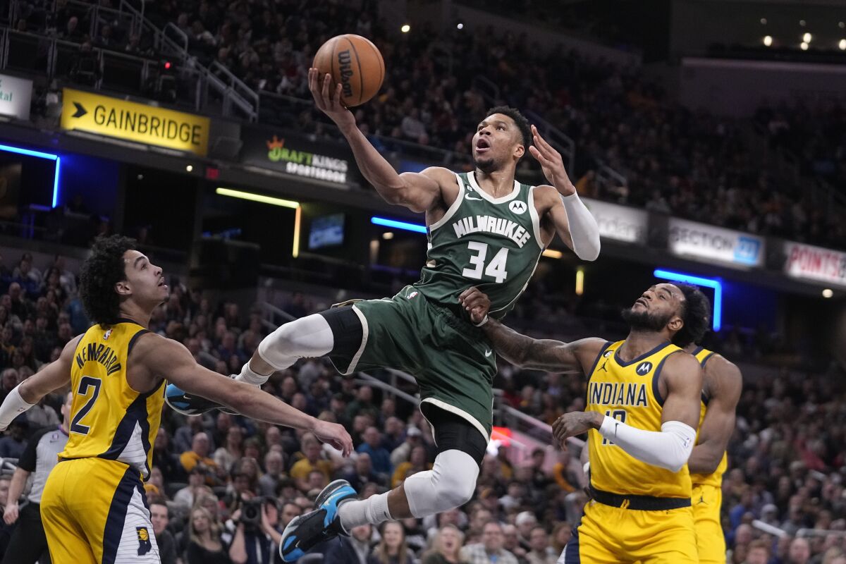 Milwaukee Bucks' Giannis Antetokounmpo (34) puts up a shot against Indiana Pacers' Andrew Nembhard (2) and Oshae Brissett (12) during the second half of an NBA basketball game, Friday, Jan. 27, 2023, in Indianapolis. (AP Photo/Darron Cummings)