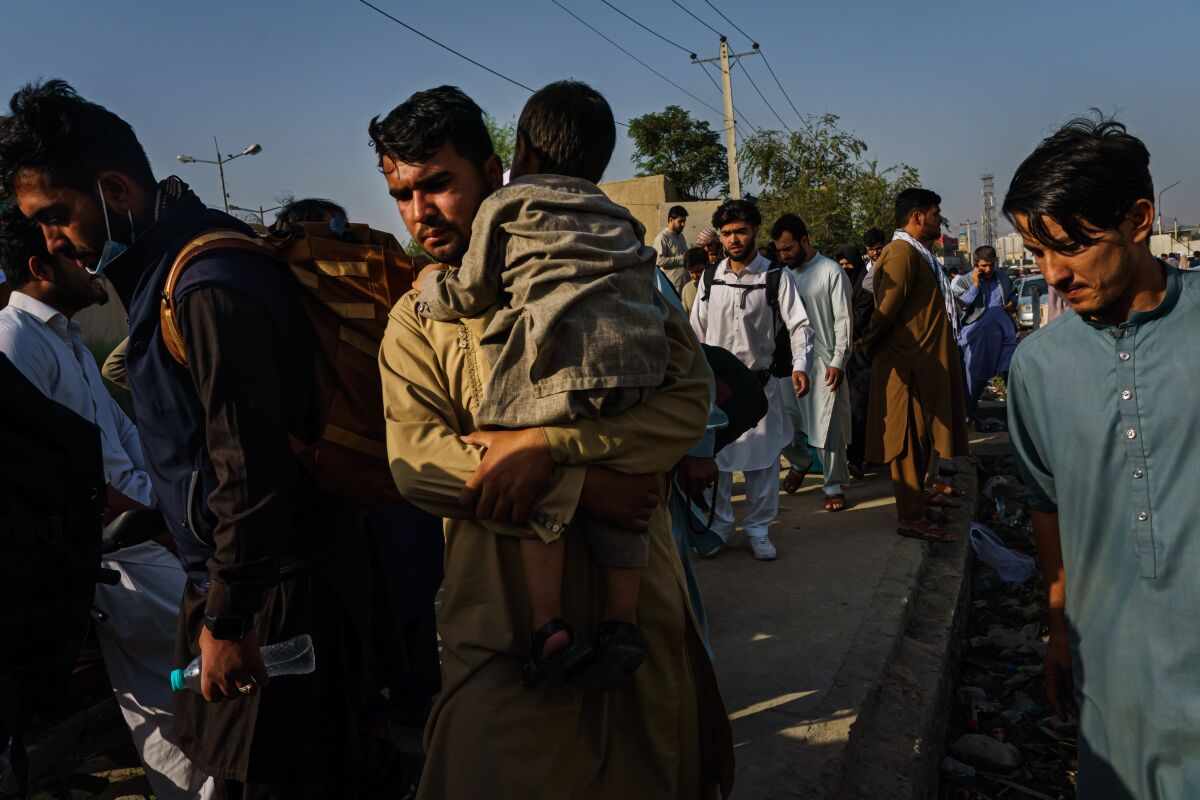 Afghans make their way the road to the military entrance of the airport for evacuations, in Kabul on, Aug. 19.