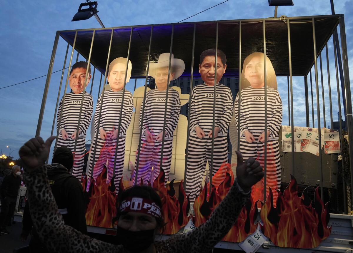 Faux flames burn at the base of a mock prison cell holding several cutout figures in black-and-white striped prison outfits. 