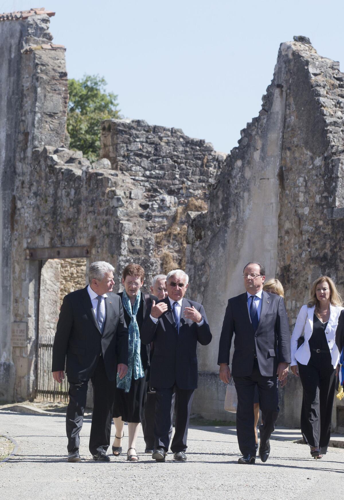 German President Joachim Gauck, left, and French President Francois Hollande, right, tour the scene of a 1944 Nazi massacre in the west-central French village of Oradour-sur-Glane with Robert Hebras, center, one of the few survivors.