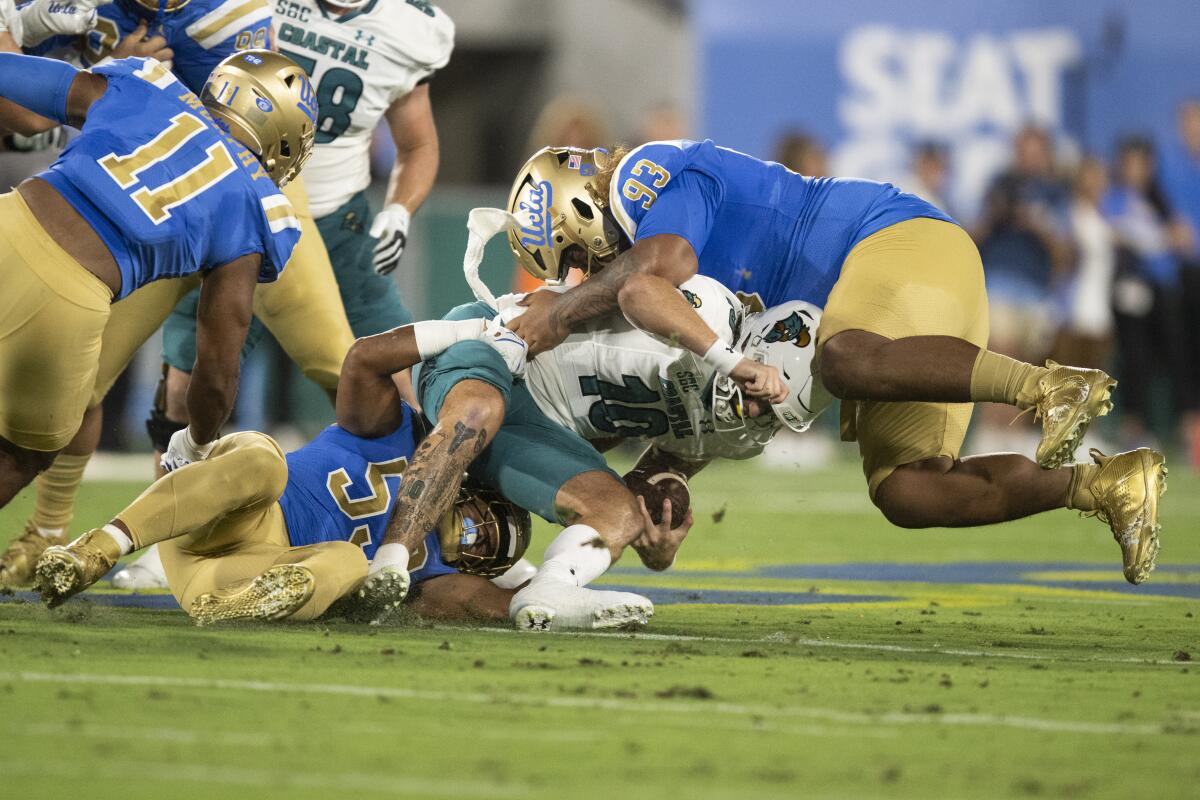 UCLA defans oyuncusu Darius Muasau ve savunma yan hakemi Jay Toia, Coastal Carolina oyun kurucusu Grayson McCall ile mücadele ediyor.