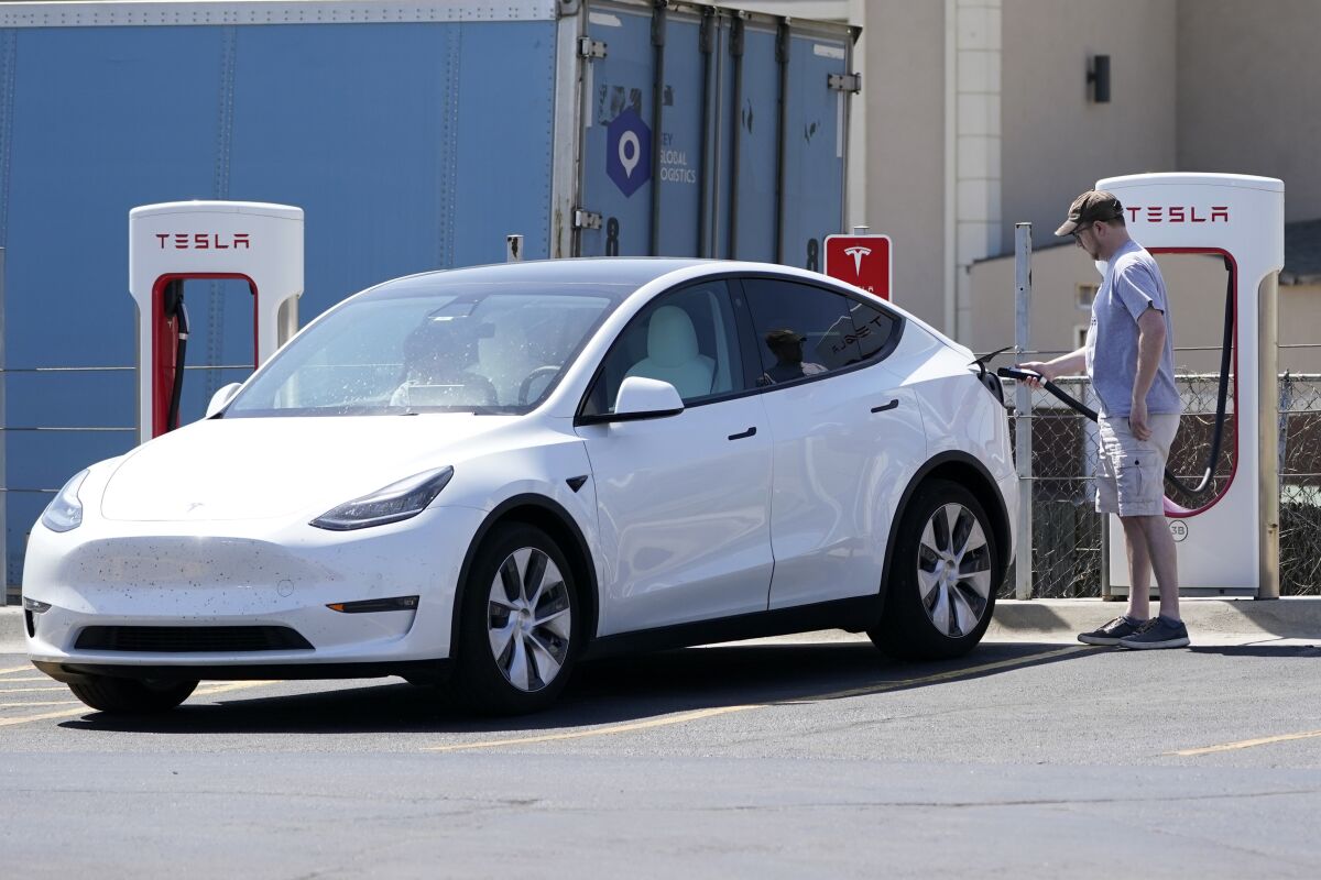 FILE - A Tesla owner charges his vehicle at a charging station in Topeka, Kan., Monday, April 5, 2021. Tesla reported 273 crashes involving partially automated driving systems, according to statistics released by U.S. safety regulators on Wednesday, June 15, 2022. But the National Highway Traffic Safety Administration cautioned against using the numbers to compare automakers, saying it didn’t weigh them by the number of vehicles from each manufacturer that use the systems, or how many miles those vehicles traveled. (AP Photo/Orlin Wagner, File)