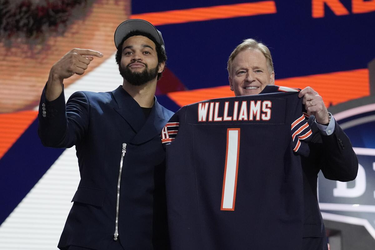 Caleb Williams points to NFL commissioner Roger Goodell, who is holding up a Williams No. 1 Chicago Bears jersey