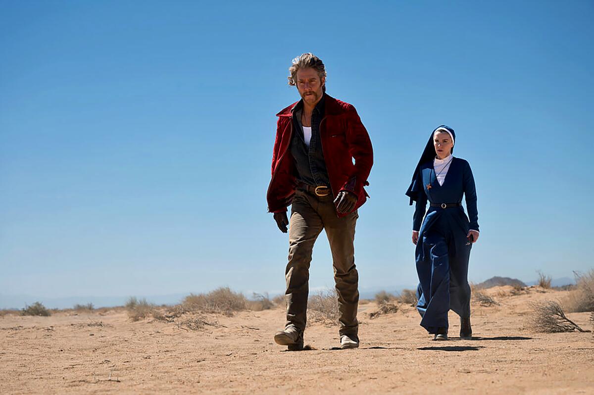 A man and nun walk through the desert.