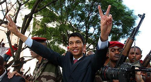 Madagascar opposition leader Andry Rajoelina, center, gives the victory sign as he parades through the streets of Antananarivo Madagascar. President Marc Ravalomanana resigned today, diplomats said, bowing to the inevitable after the army blasted its way into his offices over the weekend and let the opposition leader take control.