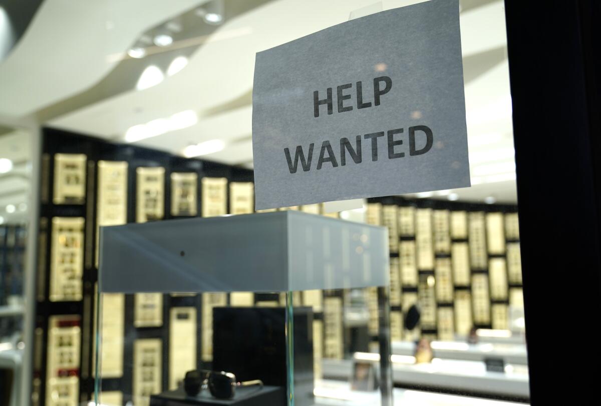 A help wanted sign in a store window