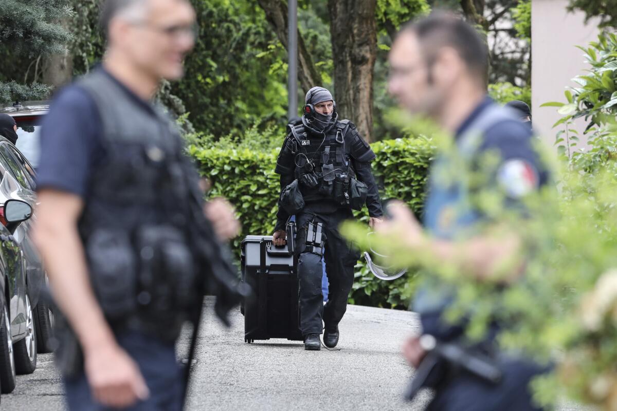 A police officer carries a suitcase during searches at a bombing suspect's home in Oullins, France, on Monday.
