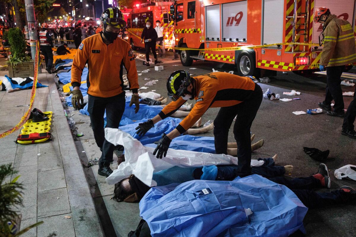 کارگران اورژانس ملحفه ها را روی اجساد در خیابان می کشند.