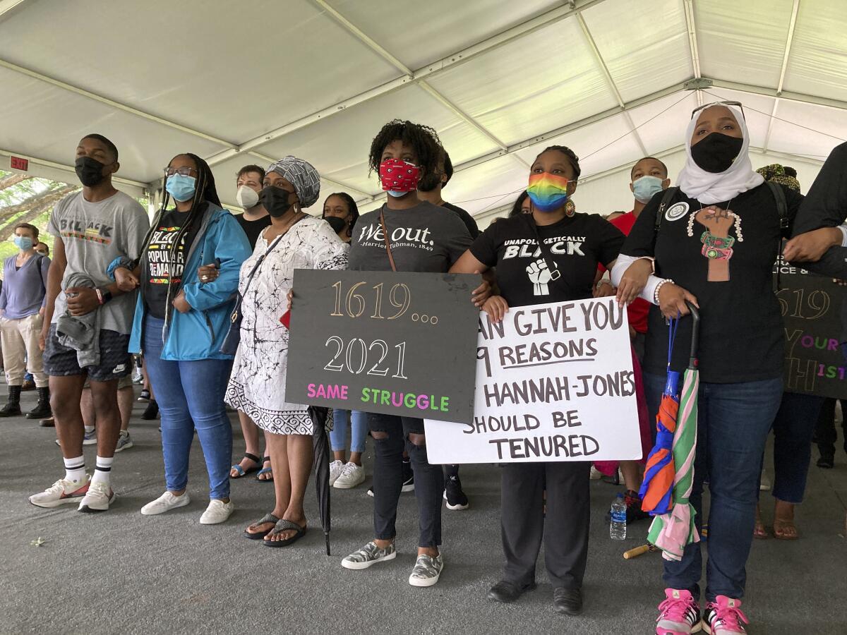 Demonstrators gather with some holding hands and others holding signs