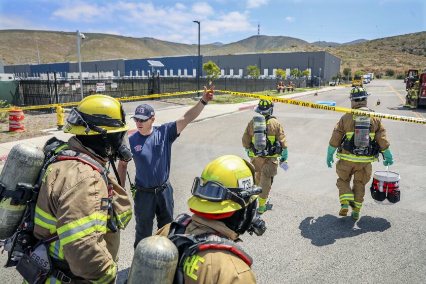 OTAY MESA MAY 16: Firefighters prepare to enter a building where a fire at an energy storage facility was burning on Thursday, May 16, 2024 in Otay Mesa, which houses lithium ion batteries. Several businesses in the area where evacuated and Donavan State was told to shelter in place. (Photo by Sandy Huffaker for The SD Union-Tribune)