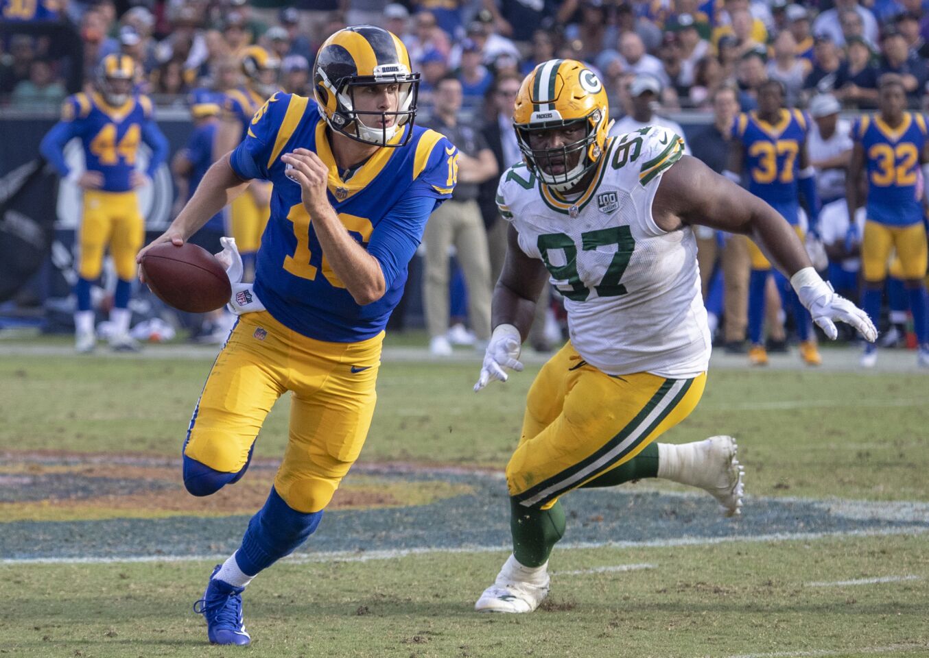 Rams quarterback Jared Goff, left, is chased out of the pocket by Green Bay Packers' Kenney Clark at the Coliseum on Sunday.