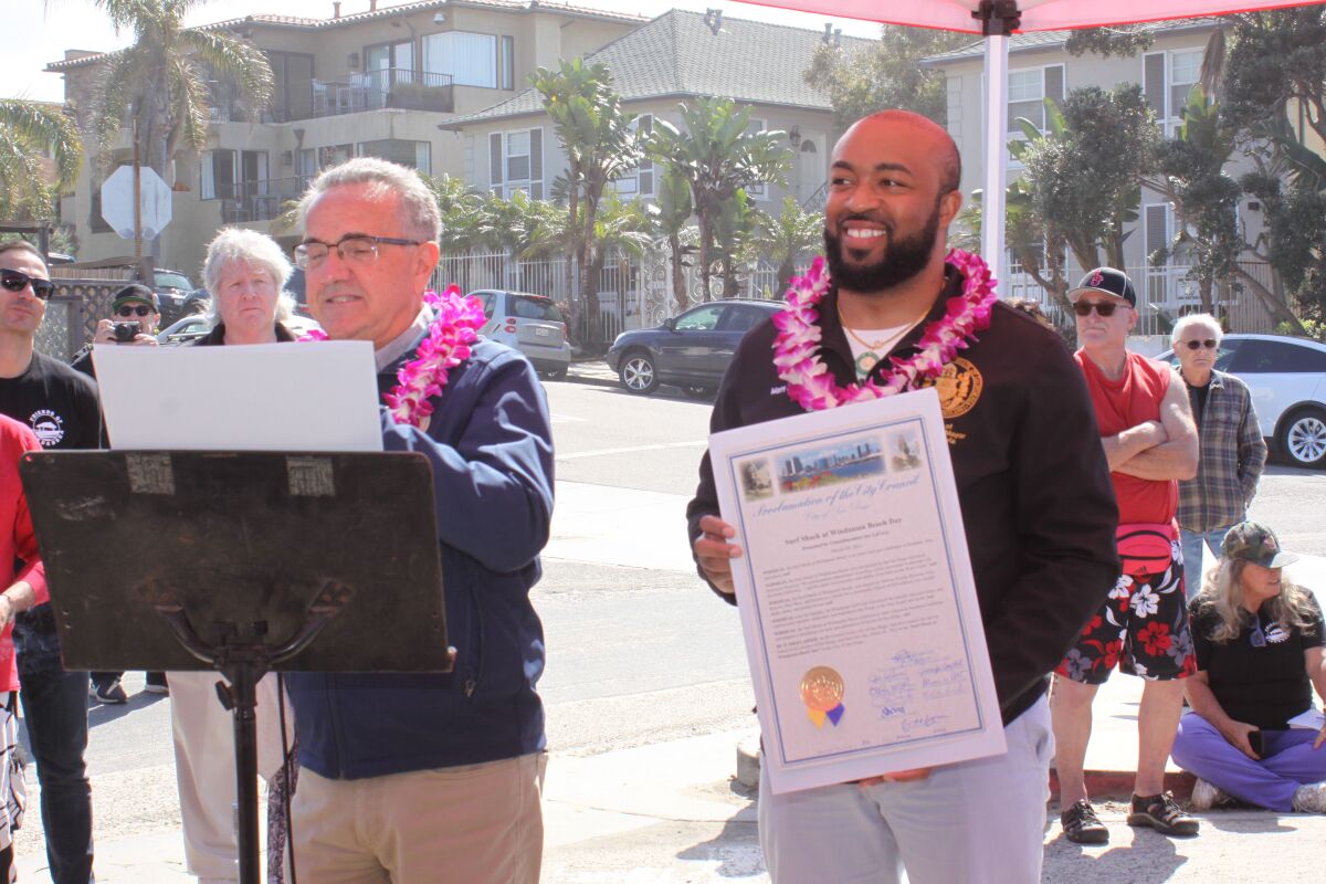 Matt Griffith (right) holds a San Diego proclamation honoring the Windansea surf shack while Councilman Joe LaCava speaks. 