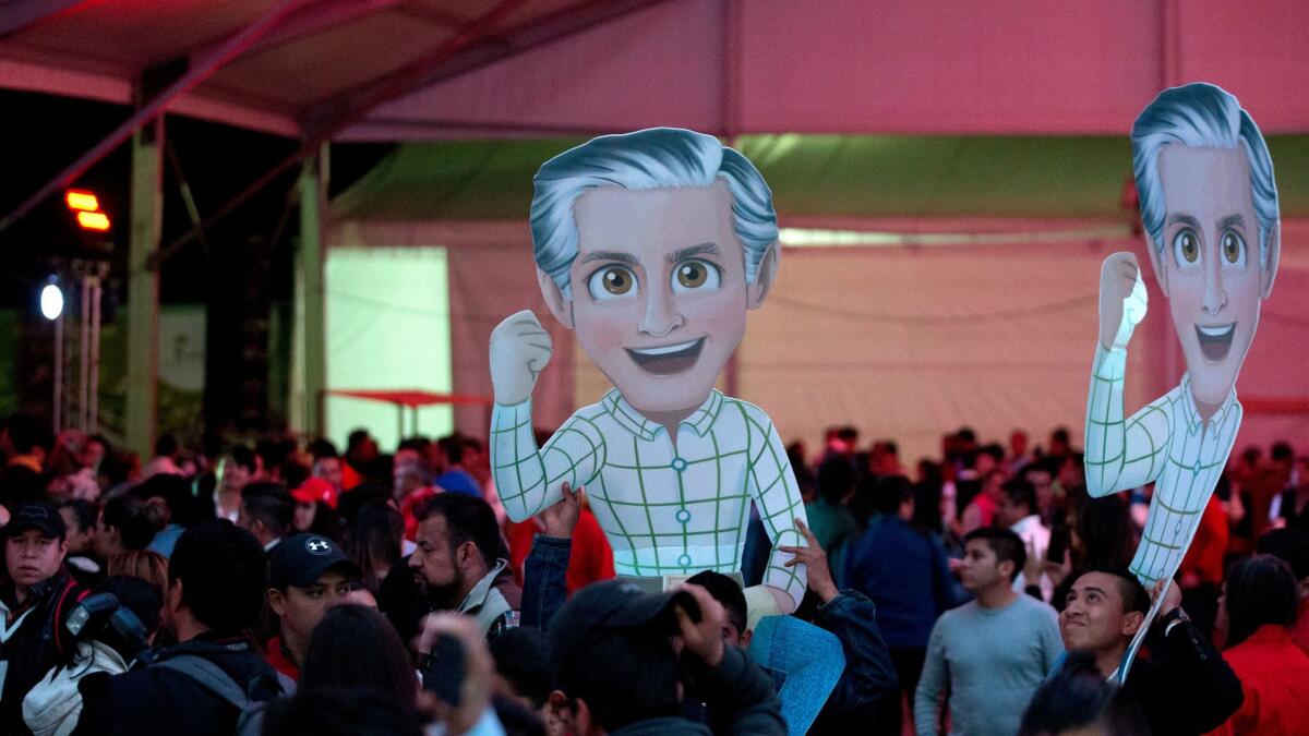 Supporters hold up cardboard cutouts depicting Alfredo Del Mazo Maza, Mexico state gubernatorial candidate for the ruling Institutional Revolutionary Party, or PRI, at the party's headquarters in Toluca on June 4, 2017.