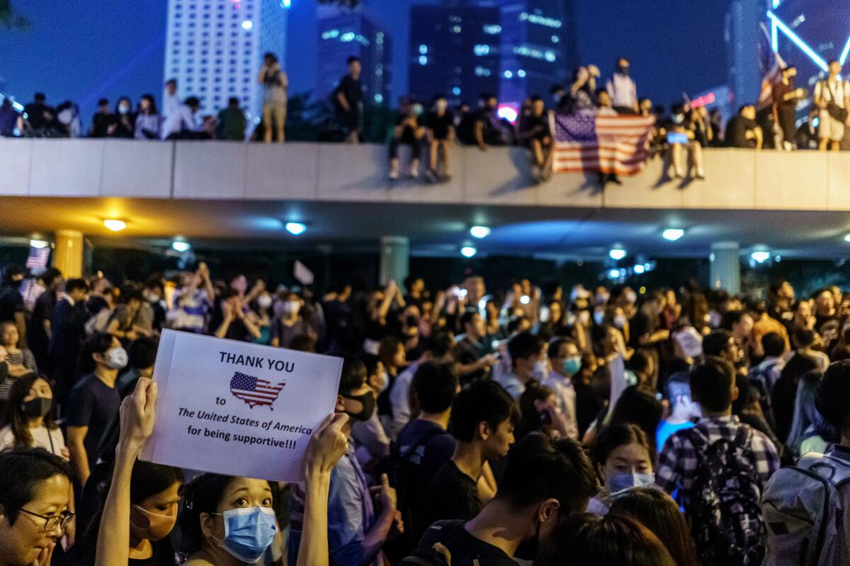 People raise their cellphones and wave American flags as they gather for the first police-sanctioned rally since the anti-mask ban law to support of the Hong Kong Human Rights and Democracy Act, a bill proposed in the U.S., in the Central district of Hong Kong.