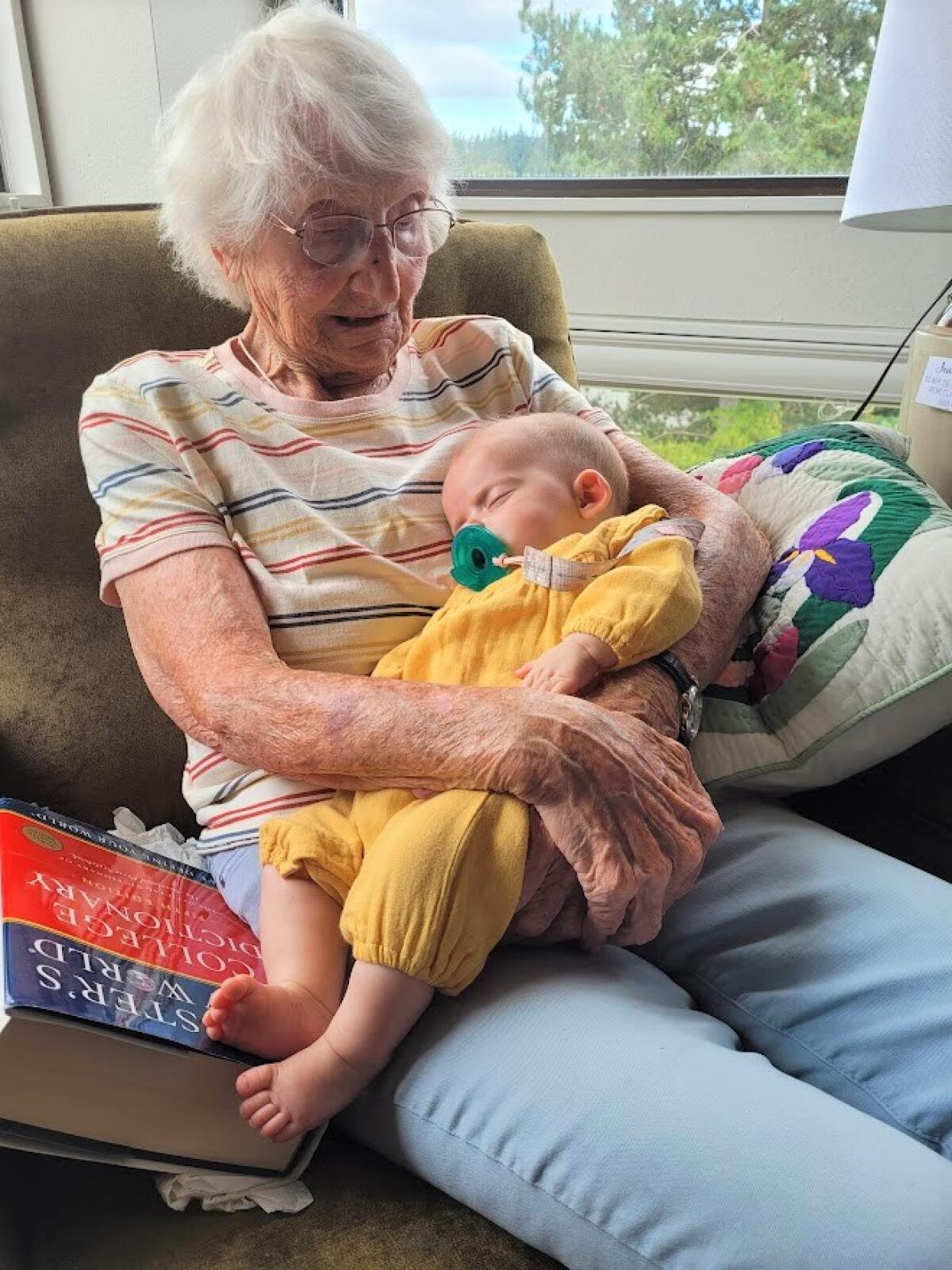 Jeanne Keevil, in 2022, with great-granddaughter Mara and a Webster's New World Dictionary.