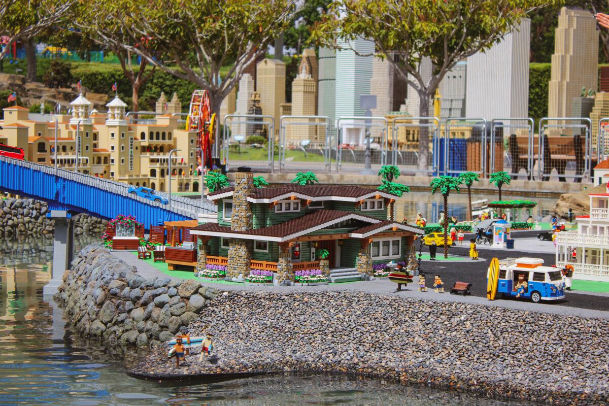 A beachside house with buildings behind, all made of Lego bricks.