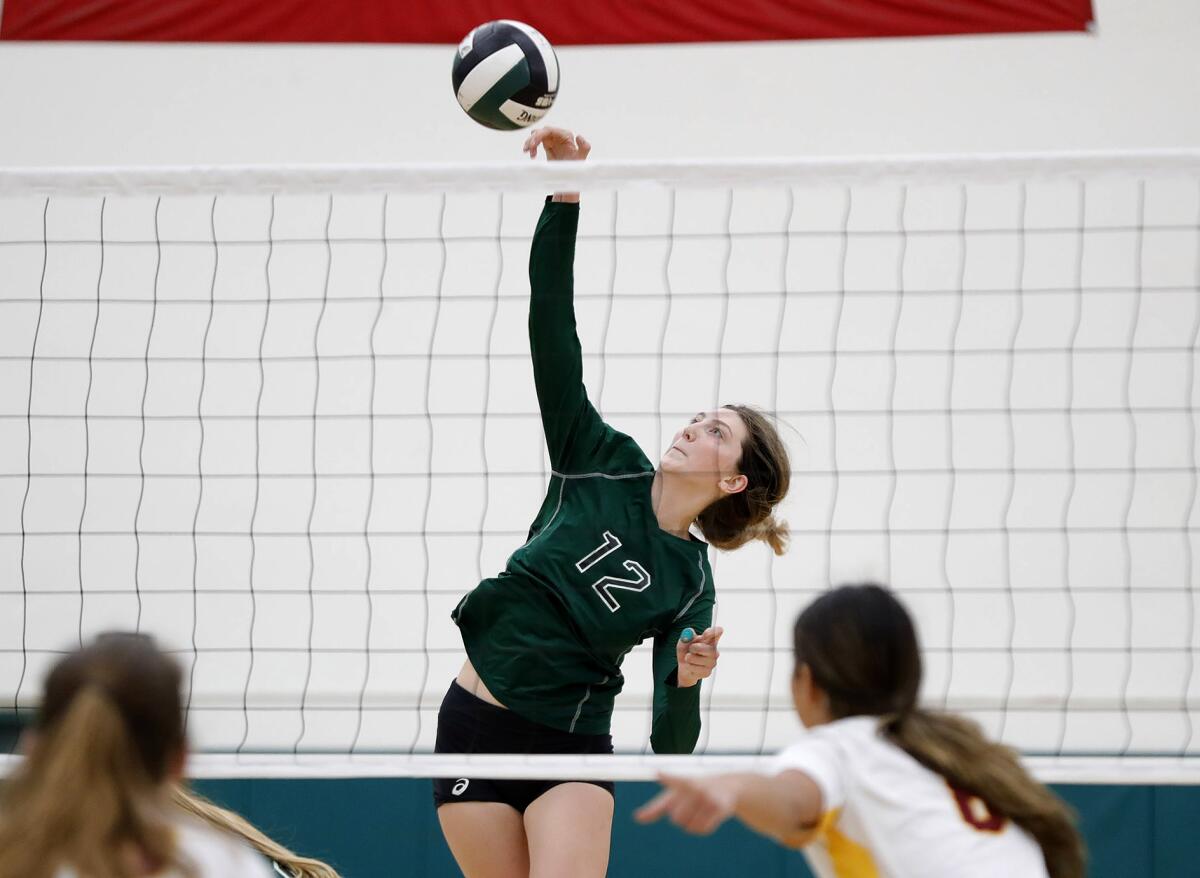 Costa Mesa's Lorelei Hobbis (12) reaches up to kill a ball during their crosstown rivalry volleyball match against Estancia.