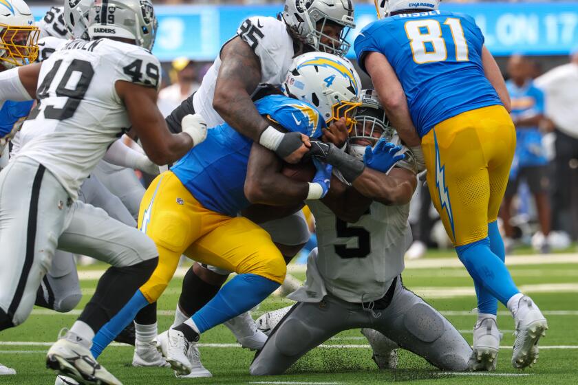 Chargers running back Gus Edwards is tackled by Las Vegas Raiders defenders during the Chargers' win Sunday at SoFi Stadium.