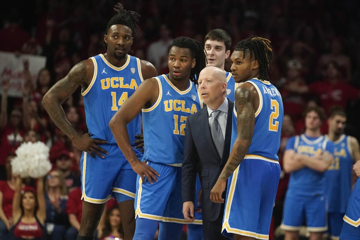 UCLA coach Mick Cronin and players stand together and look across the court.