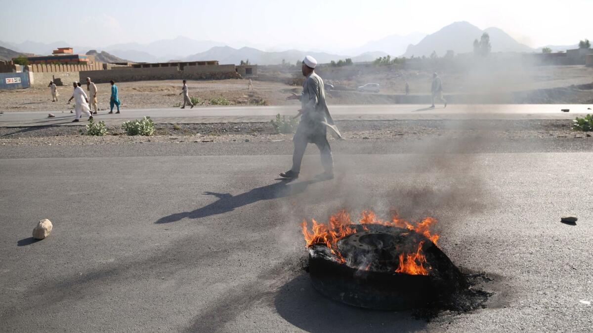 People walk near a burning tire after a suicide bomb attack in the Momandara district of Nangarhar province, Afghanistan, on Sept. 11.