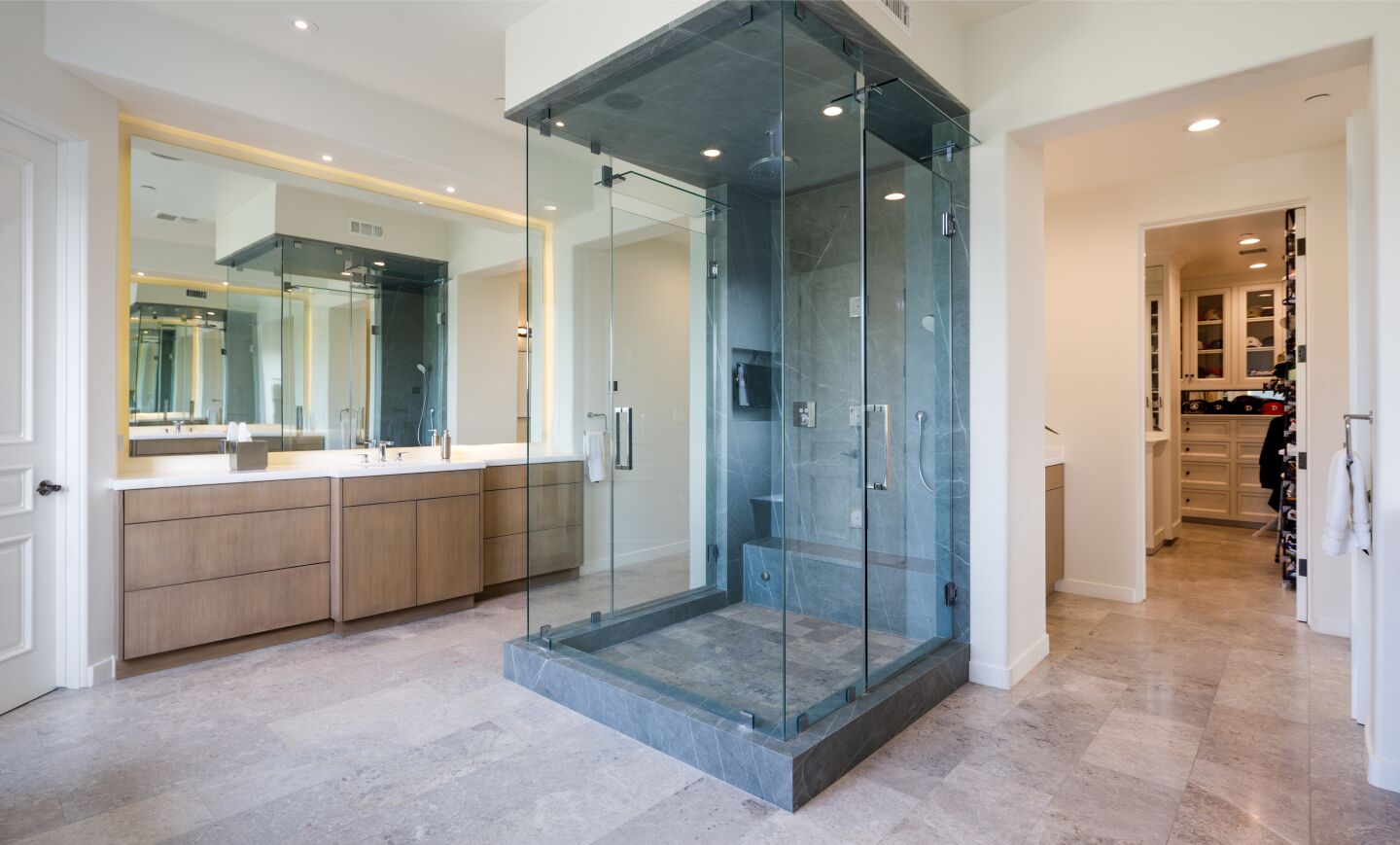 A shower with three glass walls extends from a wall.