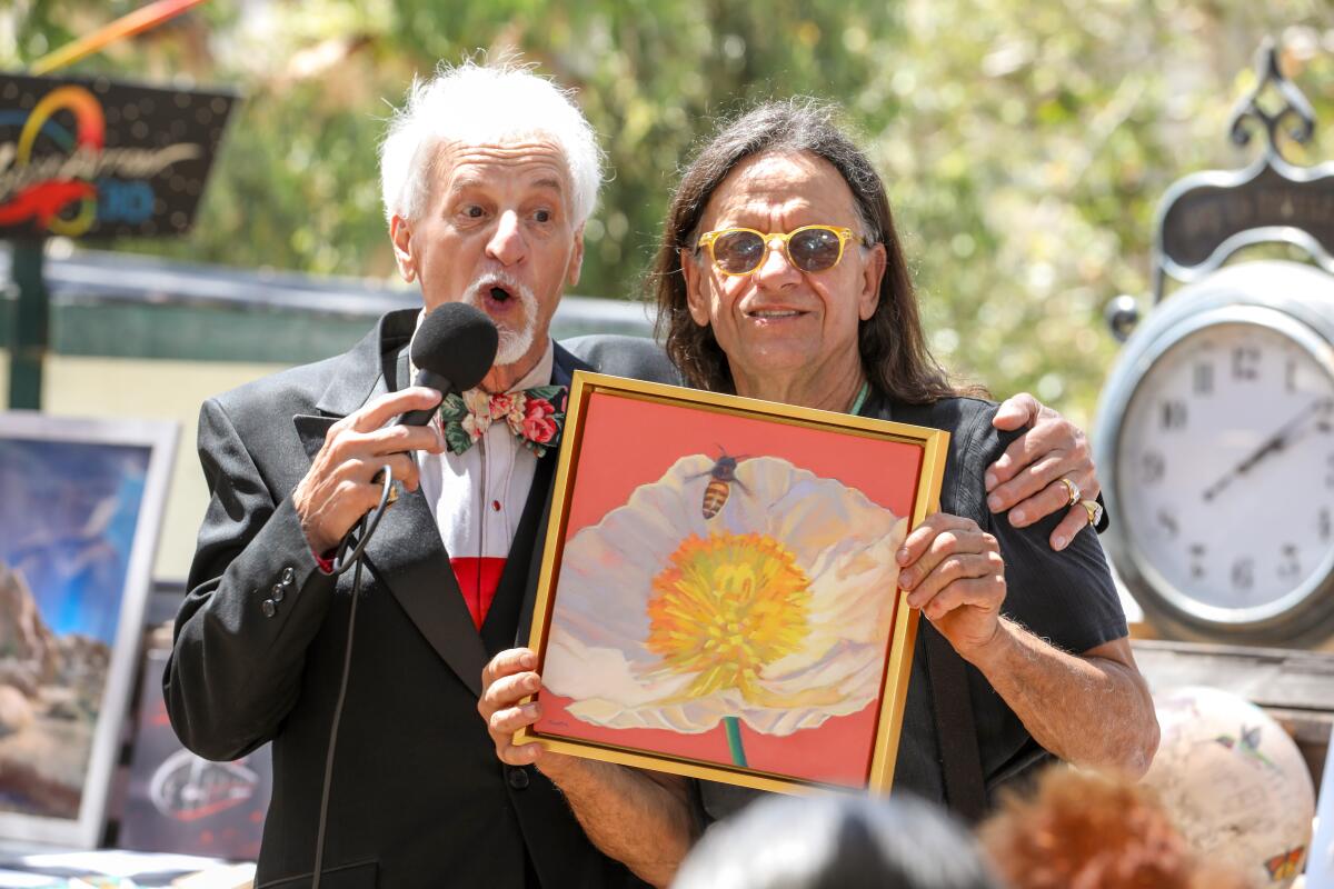 Auctioneer Tony Dezago, left, takes bids on art donated by artist Shamus Koch.  