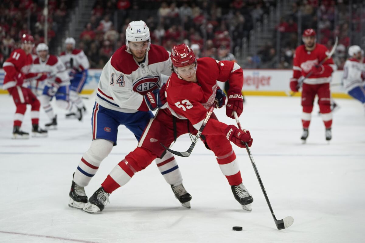 Detroit Red Wings defenseman Moritz Seider (53) clears the puck from Montreal Canadiens center Nick Suzuki (14) in the third period of an NHL hockey game Saturday, Nov. 13, 2021, in Detroit. (AP Photo/Paul Sancya)