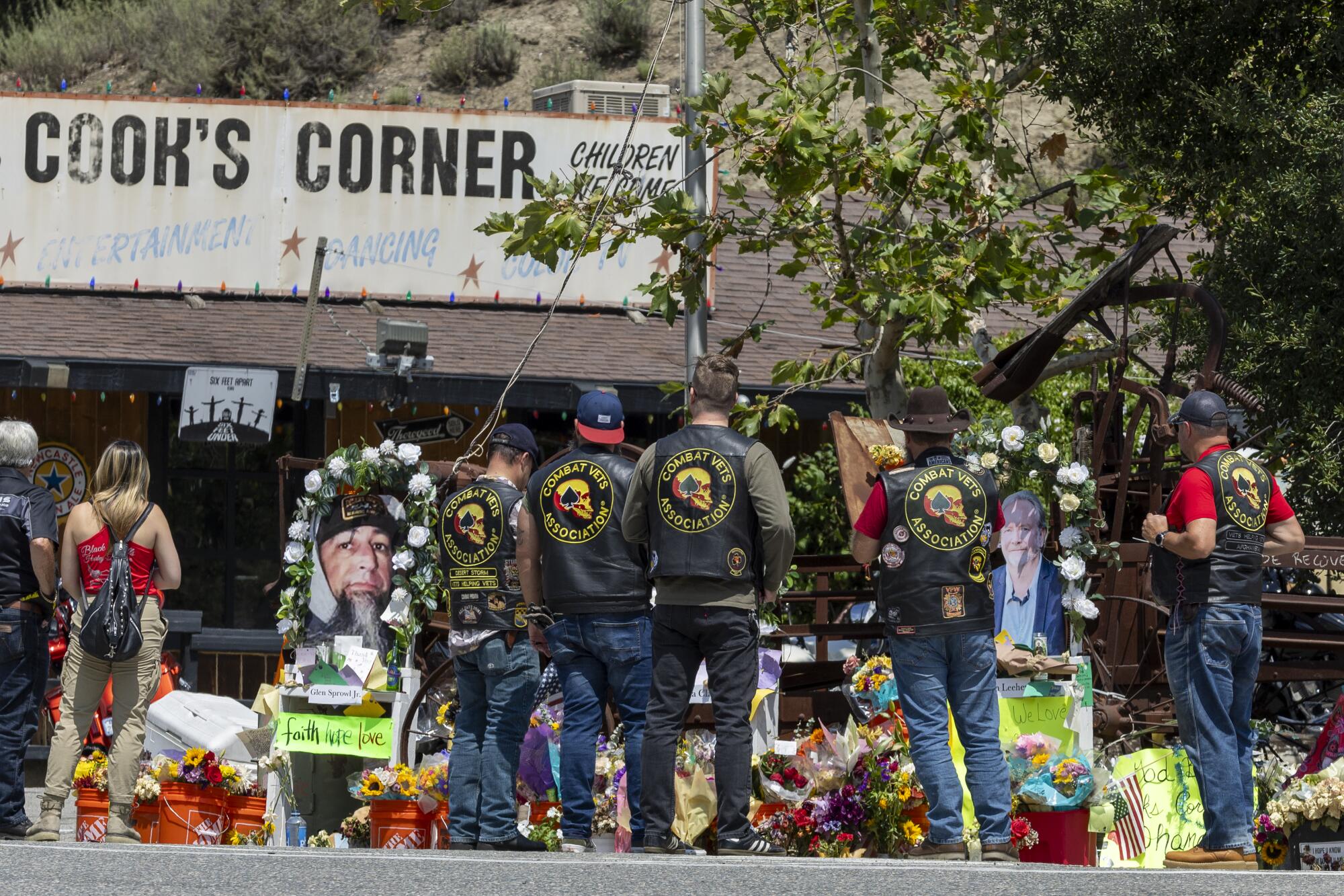 Members of the Combat Veterans Assn. motorcycle club view a growing memorial to victims.