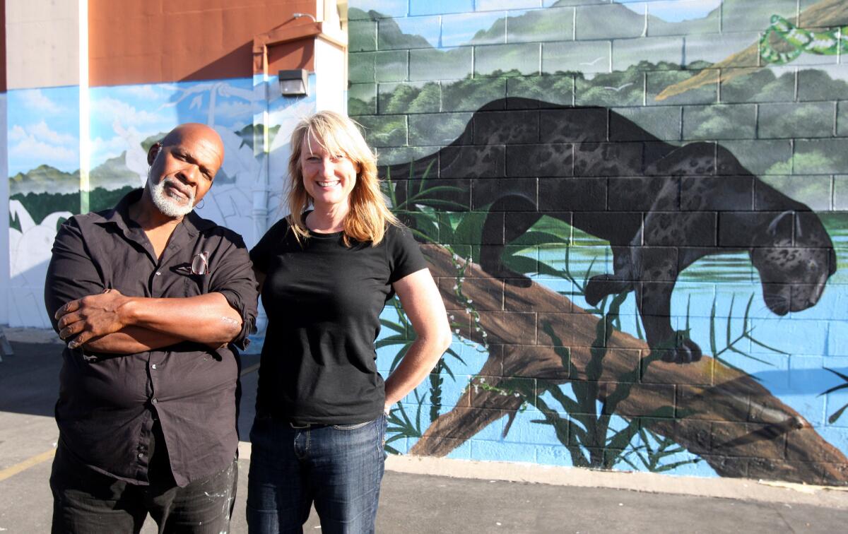 Artist Henry Goods, left, and Jenny Harris, a parent of a McKinley Elementary School student, at the mural Goods is painting for the school. Harris helped secure funds to hire Goods, who will incorporate drawings by students into the mural.