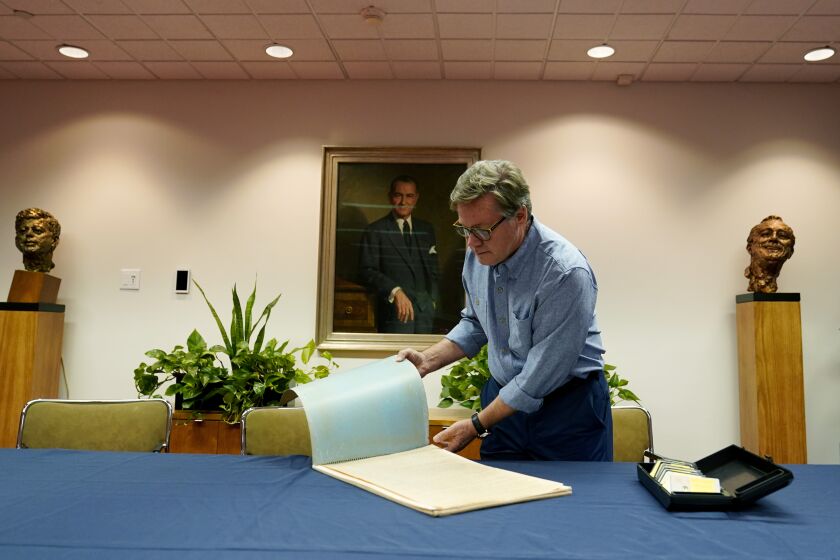 Peter Mangan flips through a large folder of newspaper clippings at the Lyndon B. Johnson's presidential library as he prepares to make a donation to the library, Wednesday, Aug. 31, 2022, in Austin, Texas. The family of the late Associated Press reporter James W. Mangan has donated to the library cassette tapes containing interviews the reporter did that led to a 1977 story in which a Texas voting official detailed how three decades earlier, votes were falsified to give Johnson a slim victory in a U.S. Senate primary. (AP Photo/Eric Gay)