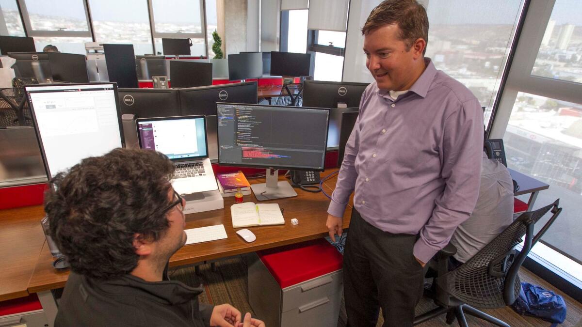 Mark Field, chief technology officer at Thermo Fisher Scientific, right, chats with software engineer Emilio Escobedo, born in Chula Vista but educated in Tijuana.