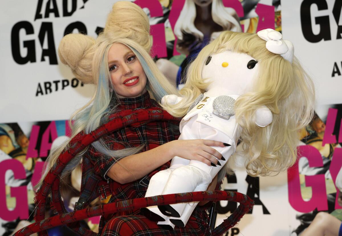 Lady Gaga poses for photographers with a Hello Kitty doll during a news conference to promote her album "Artpop" in Tokyo on Sunday.