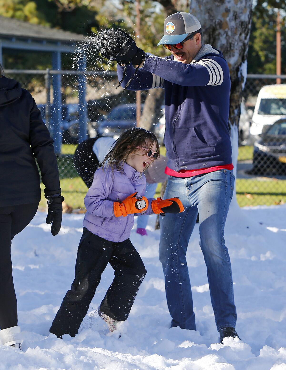 Sean Norris sprinkles snow over his daughter, Kayla, 6, during the annual Snow Land event.