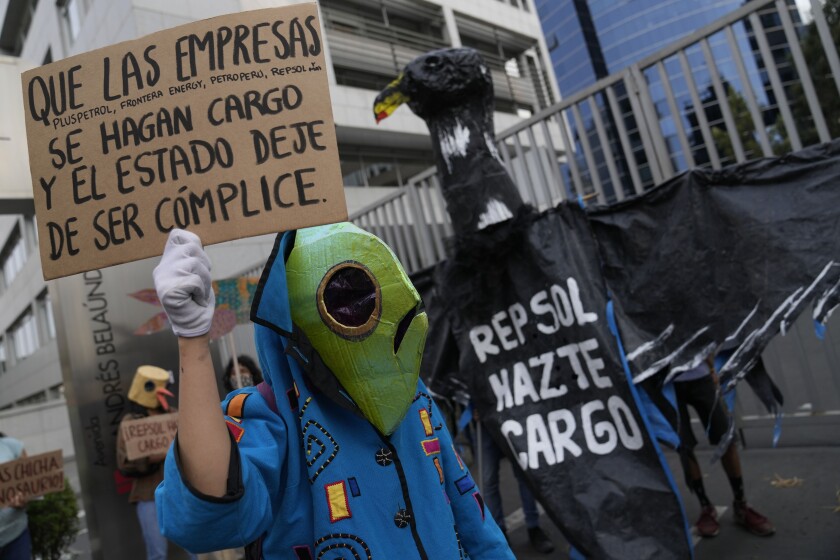 A demonstrator wearing a fish mask protests in front of the Repsol office in Lima, Peru, Thursday, Jan. 26, 2022. The demonstrators were there to protest after Peru declared an environmental emergency after announcing that 21 beaches on the Pacific coast were contaminated by an oil spill at a refinery run by Spain-based Repsol, following surging waves caused by the eruption of an underwater volcano near Tonga. (AP Photo/Martin Mejia)