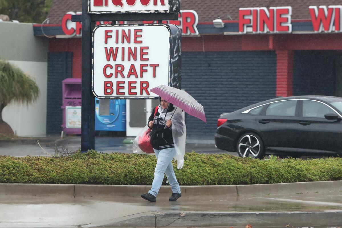 A woman walks through the rain along Baker Street in Costa Mesa.