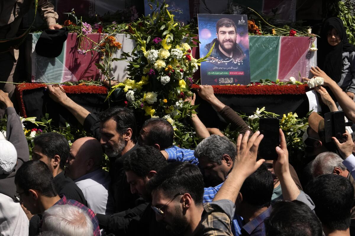 Iranian mourners reach out, trying to touch flag-draped coffins.