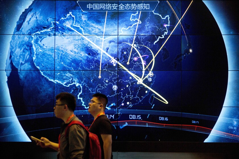 FILE - In this Sept. 12, 2017, file photo, attendees walk past an electronic display showing recent cyberattacks in China at the China Internet Security Conference in Beijing. Cybersecurity and space are emerging risks to the global economy, adding to existing challenges posed by climate change and the coronavirus pandemic, the World Economic Forum said in a report Tuesday, Jan. 11, 2022. (AP Photo/Mark Schiefelbein, File)