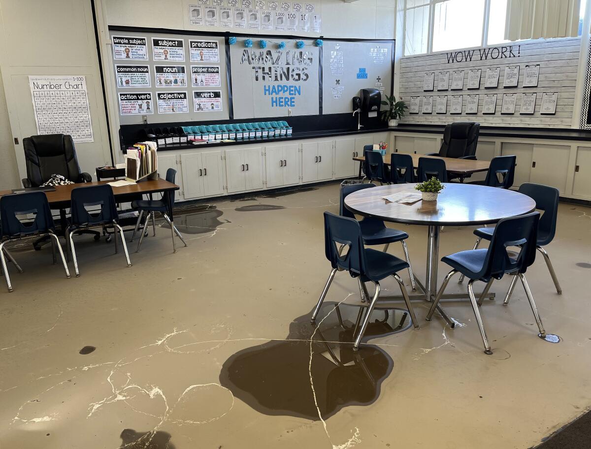 A classroom with puddles near and under tables and chairs.