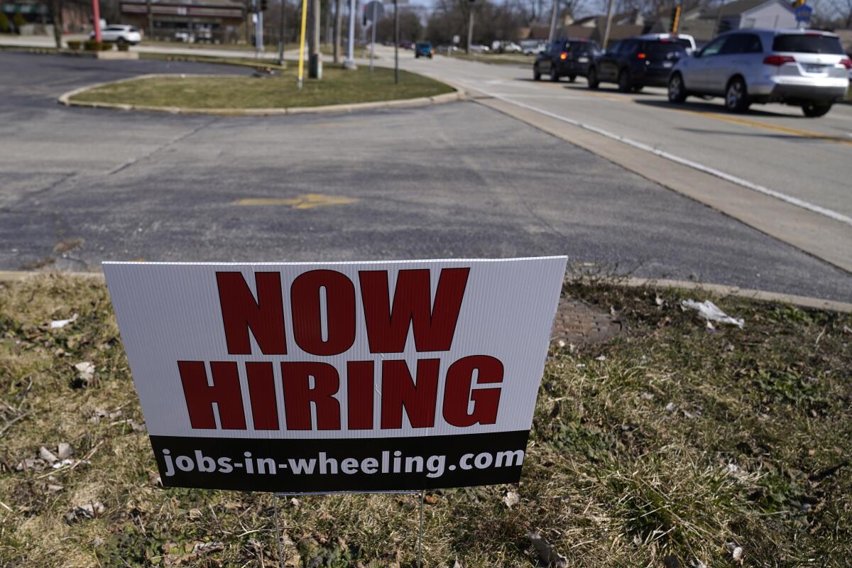 A lawn sign reads "Now Hiring."