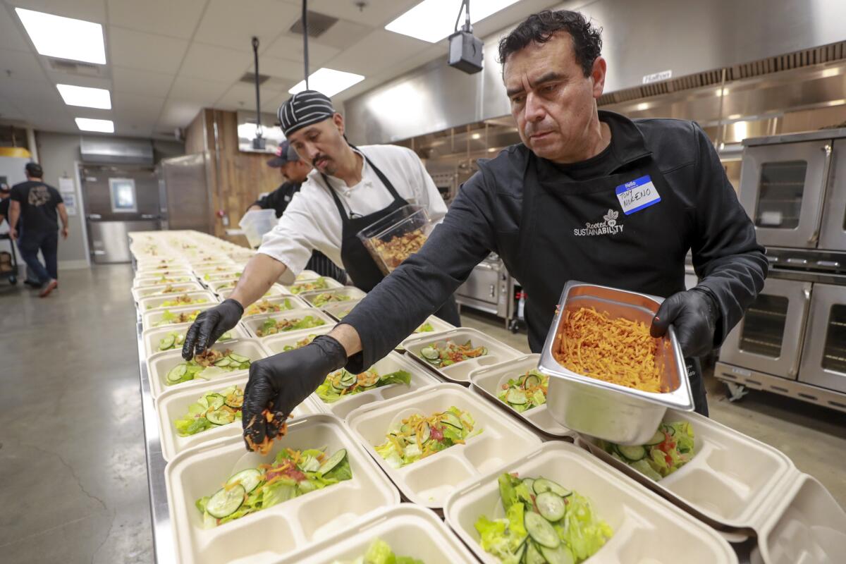 Tony Moreno, right, and Jose Pablo place salad items onto plates as they and other O'side Kitchen Collaborative volunteers, who are kitchen staff workers at various local restaurants, prepare soup and salad dinners for seniors at the Green Oceanside Kitchen on Tuesday.