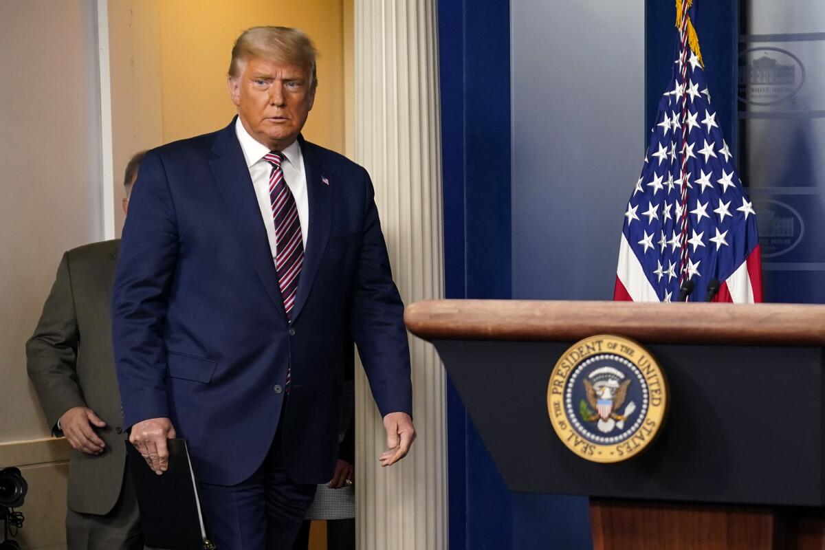 President Trump walks toward a lectern with the presidential seal in the White House briefing room