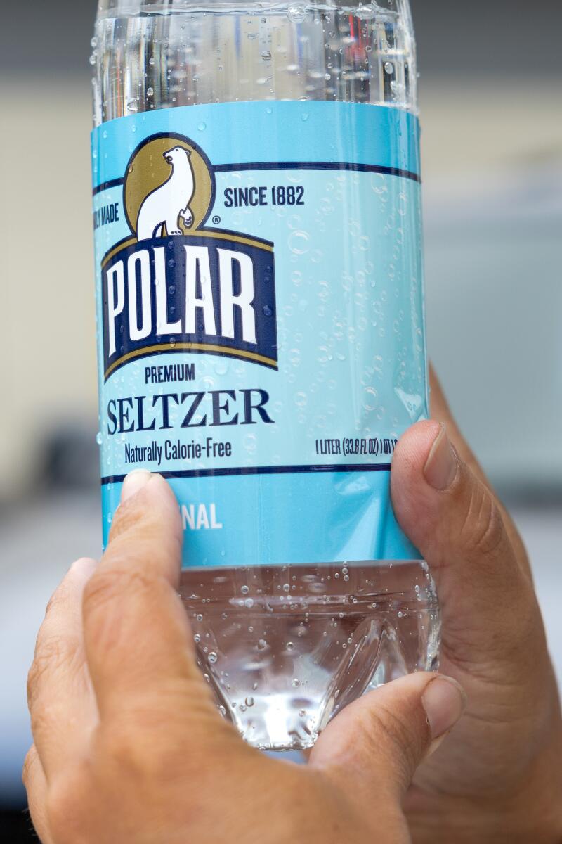 A hand holding up a Polar water bottle and pointing to the label.
