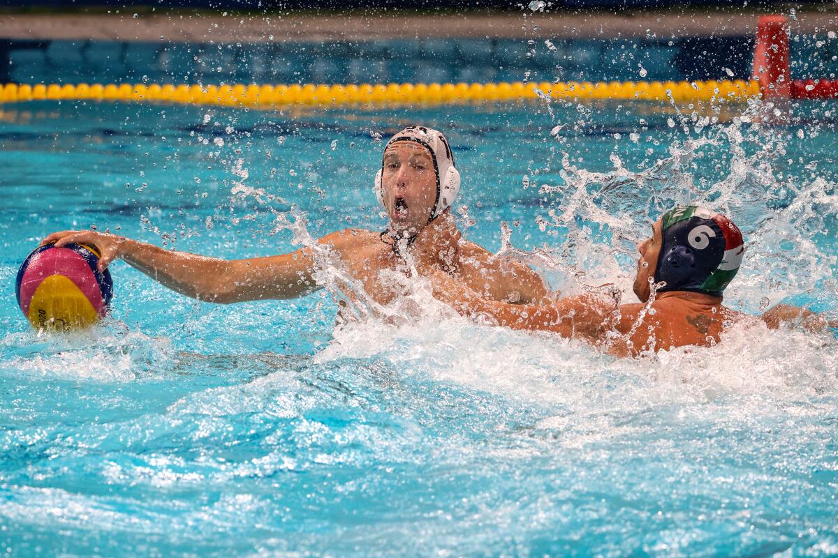 U.S. driver Ben Stevenson holds the ball above the pool surface with Norbert Hosnyanszky splashing and reaching for him.