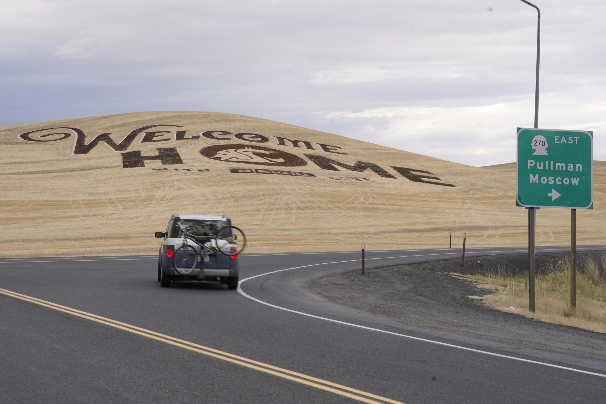 A sign etched into a harvested wheat field welcoming students back to Washington State University is shown.